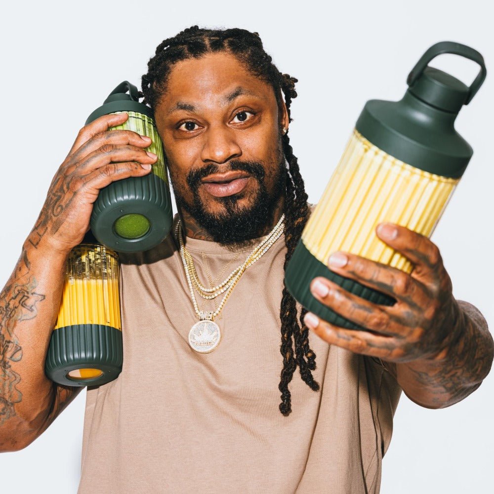 Marshawn Lynch (Beast Mode) holding the Beastmode blender and bottle accessory in front of a white background | Forest Green
