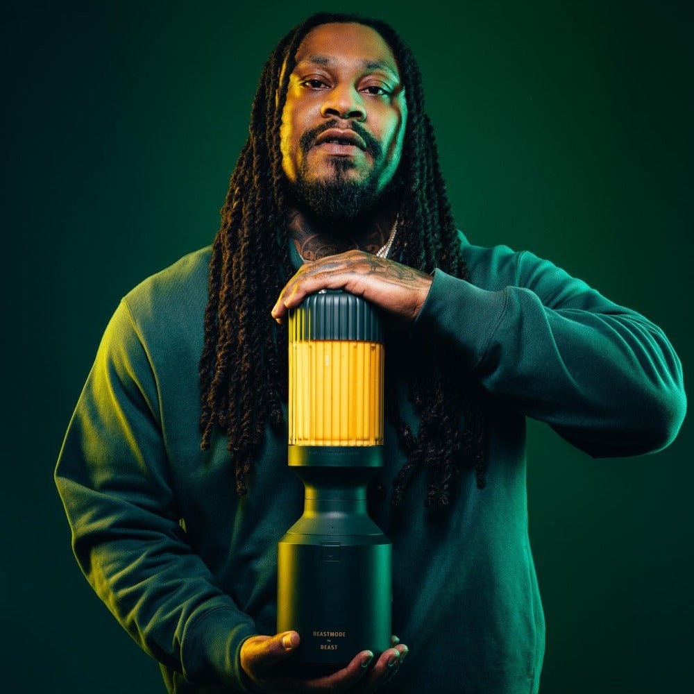 Marshawn Lynch (Beast Mode) holding the Beastmode blender in front of a green background | Forest Green