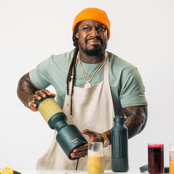 Marshawn Lynch (Beast Mode) wearing an orange hat, a green shirt, and a white apron, using the Beastmode Blender	